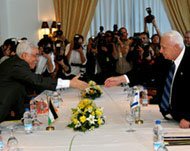 Abbas and Sharon reach across the negotiating table to shake hands.