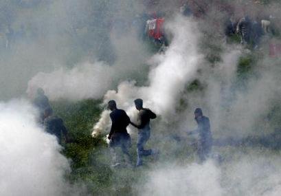 Protestors run for air through a thick cloud of tear gas.
